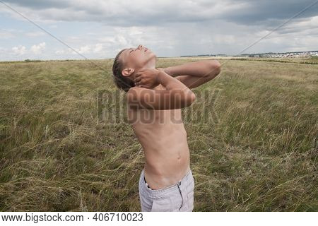Boy In Shorts Stands In The Field. Boy Looks To The Sky. Dreamer Guy