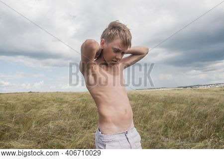 Boy In Shorts Stands In The Field. Boy Looks To The Sky. Dreamer Guy