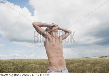 Boy In Shorts Stands In The Field. Boy Looks To The Sky. Dreamer Guy