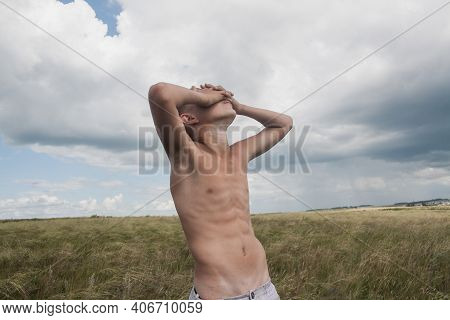 Boy In Shorts Stands In The Field. Boy Looks To The Sky. Dreamer Guy