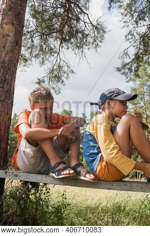 Two Boys In Shorts Cross The Road In The Countryside.
