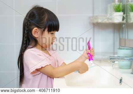 Asian Cute Child Girl Or Kid Squeeze The Toothpaste Into Toothbrush Before Brushing Her Teeth In The