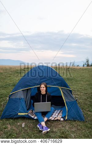 Woman Working On Laptop In Tent In Nature. Young Freelancer Sitting In Camp. Relaxing In Camping Sit