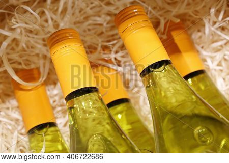 White Wine Bottles In A Wooden Box With Shavings. Liquor Store, Online Order And Delivery Wine In Co