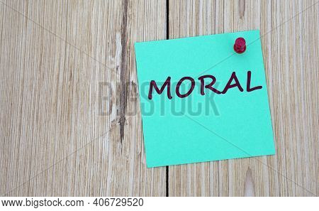Moral - Word Written On A Green Sheet For Notes, Which Is Pinned To A Light Wooden Board. Info Conce