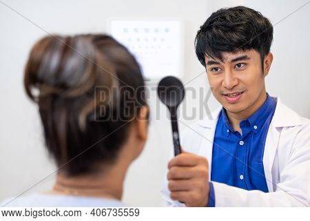 Selective Focus At Optometrist Face. While Doctor Using Penlight And Subjective Refraction To  Exami