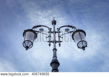 Street Lamp Seen From Below With The Blue Sky In The Background With Some Clouds.