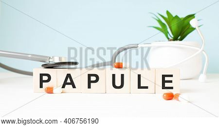 The Word Papule Is Written On Wooden Cubes Near A Stethoscope On A Wooden Background. Medical Concep