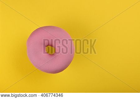 Close Up One Pink Glazed Ring Donut Over Yellow Background, Elevated Top View, Directly Above