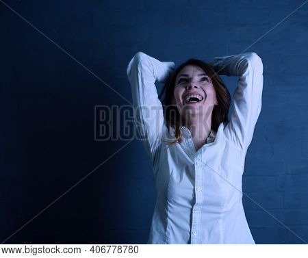 Young Brunette Woman In White Shirt Laughs Cheerfully On Black Background