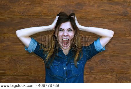 Young Woman In Denim Shirt With Open Mouth On Brown Background