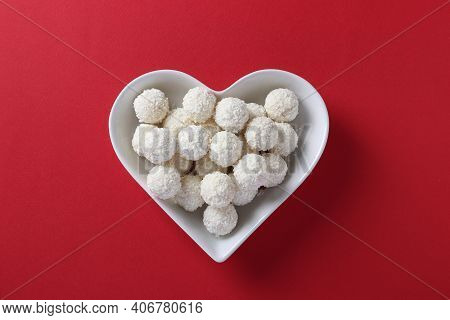 Sweet Coconut Rafaello Candies In A Heart-shaped Plate On A Red Background. View From Above