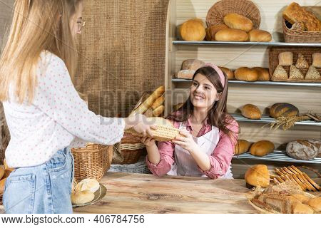 After Paying For The Bread, An Attractive Saleswoman Serves Half A Loaf Of Bread To A Young Customer