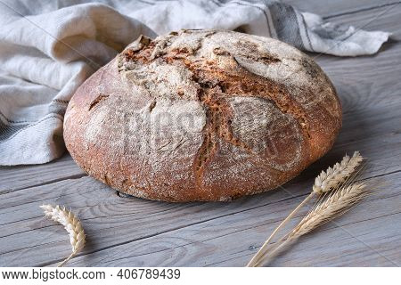 No Knead Handmade Loaf On Cutting Board On Wood With Linen Towel, Spelt Ears. German Bauernbrot Mean