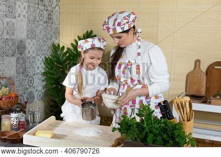 In The Kitchen, Mum Teaches Her Daughter How To Sift Wheat Flour For Pizza Dough. Family Learning In