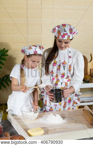 In The Kitchen, Mum Teaches Her Daughter How To Sift Wheat Flour For Pizza Dough. Family Learning In