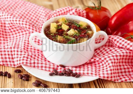 Traditional Bean Soup With Vegetables And Potatoes On A Wooden Background With Garlic.