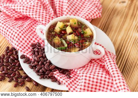 Delicious Soup Of Fresh Red Beans With The Addition Of Meat, Potatoes And Herbs On A Wooden Backgrou