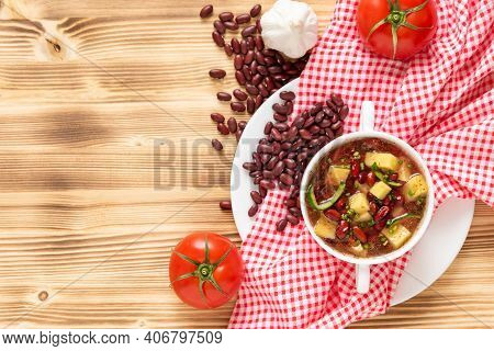 Delicious Soup Of Fresh Red Beans With The Addition Of Meat, Potatoes And Herbs On A Wooden Backgrou
