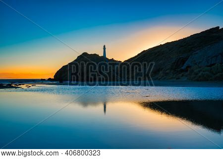Castlepoint Lighthouse And The Early Signs Of Sunlight Reflected In The Calm Waters Of The Lagoon As