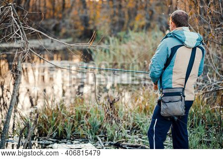 A Man Fisherman Fishing In The River With A Fishing Rod