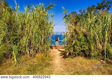 A Woman Hiker With A Backpacker In A Reeds Path Looking The Sea Of Strunjan, Slovenia