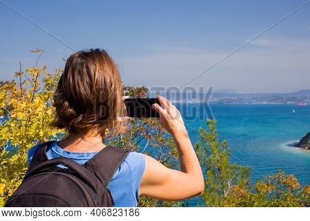 A Woman Hiker With A Backpacker Taking A Photo Of The Sea With Her Smartphone. Strunjan, Slovenia