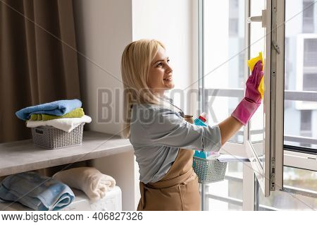 Smiling Black Woman Cleaning Windows With Glass Cleaner