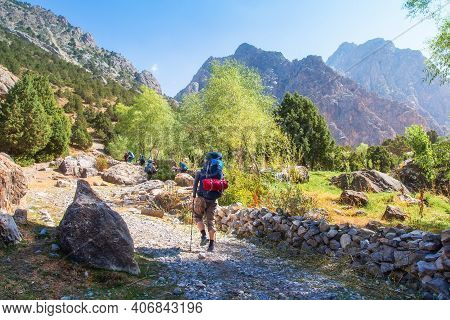Group Tourists With Backpacks Hiking In Fann Mountains In Tajikistan. Hikers On A Mountain Trail In 