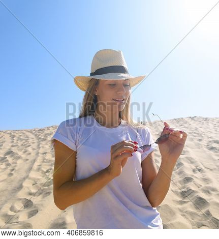 Young Woman In A Hat Holding Glasses While In The Desert