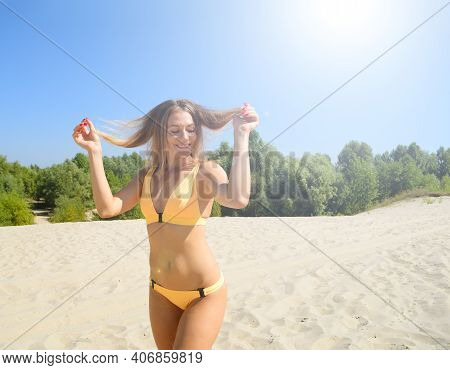Young Woman In Swimsuit Smiling With Lush Hair Standing On The Sand