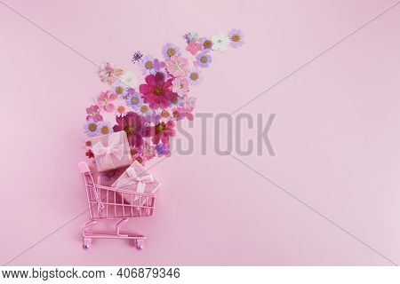 Flowers Fly Out Of The Pink Shopping Cart On A Pink Background. Season Sale, Spring Shoping Concept.