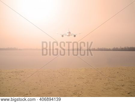 Airplane Over The Lake In The Orange Sky With The Sun. Nature And Transport