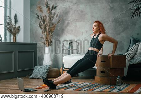 The Beauty Woman Goes In For Sports At Home. Cheerful Sporty Woman With Red Hair Shakes Biceps, Do P