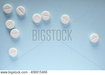 White Pills Lie On A Sheet Of Blue Paper. Close-up. Light Background Or Backdrop On The Theme Of Med
