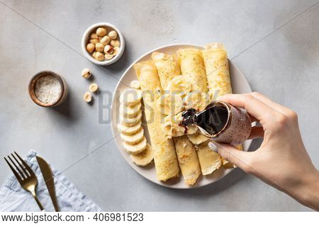 Female Hand Pours Date Syrup Over Rolled Banana Pancakes. Healthy Vegan Food Concept. Blurred Backgr