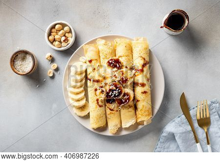 Rolled Crepes With Banana, Nuts, Coconut And Date Syrup. Healthy Vegan Breakfast Concept. Gray Backg