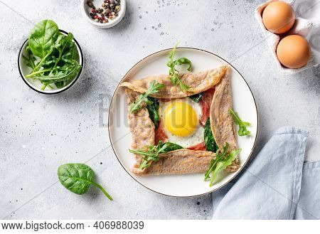 French Buckwheat Crepe With Egg, Ham And Spinach On Gray Background. Galette Bretonne. Flat Lay.