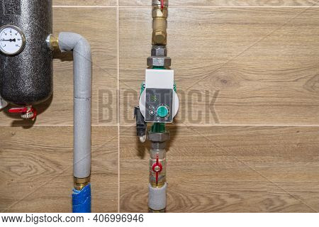 Water Circulation Pump For Underfloor Heating In A Modern Gas Boiler Room Lined With Ceramic Tiles.