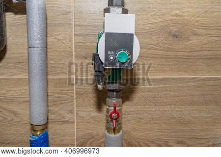 Water Circulation Pump For Underfloor Heating In A Modern Gas Boiler Room Lined With Ceramic Tiles.
