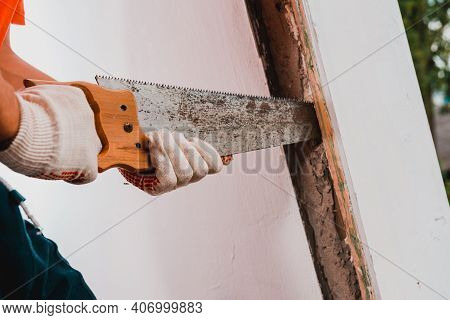 The Man With A Hand Saw Cuts The Mounting Wool Around The Window Frame, Installation Of An Old Woode