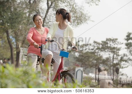 Grandmother and granddaughter riding tandem bicycle, Beijing