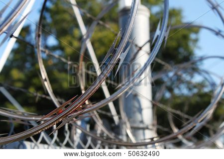 Large metal fence with barbwire and razor wire