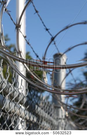 Large metal fence with barbwire and razor wire