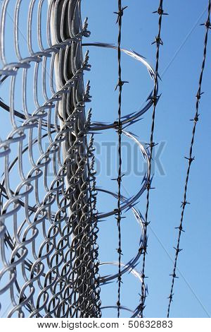 Large metal fence with barbwire and razor wire