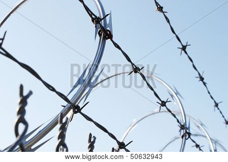 Large metal fence with barbwire and razor wire