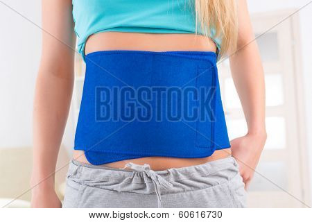 Woman wearing neoprene slimming belt at home