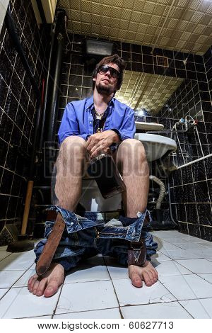 Drunk Man Sits In A Toilet With A Bottle Of Whiskey