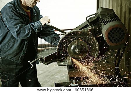 Industrial worker cutting and welding metal with many sharp sparks