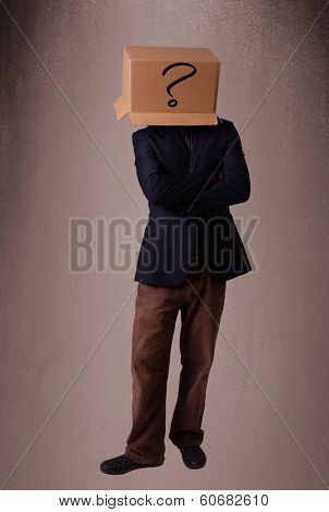 Young man standing and gesturing with a cardboard box on his head with question mark